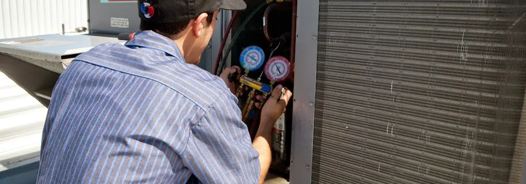 HVAC technician servicing a condenser unit in Pike Creek